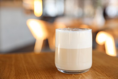 Photo of Glass of aromatic coffee on wooden table in cafe, closeup. Space for text