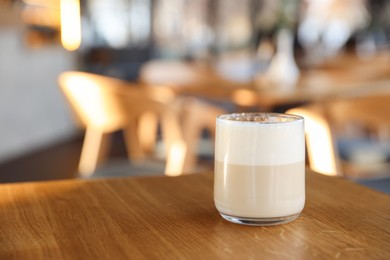 Photo of Glass of aromatic coffee on wooden table in cafe, closeup. Space for text