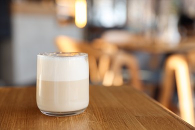 Photo of Glass of aromatic coffee on wooden table in cafe, closeup. Space for text