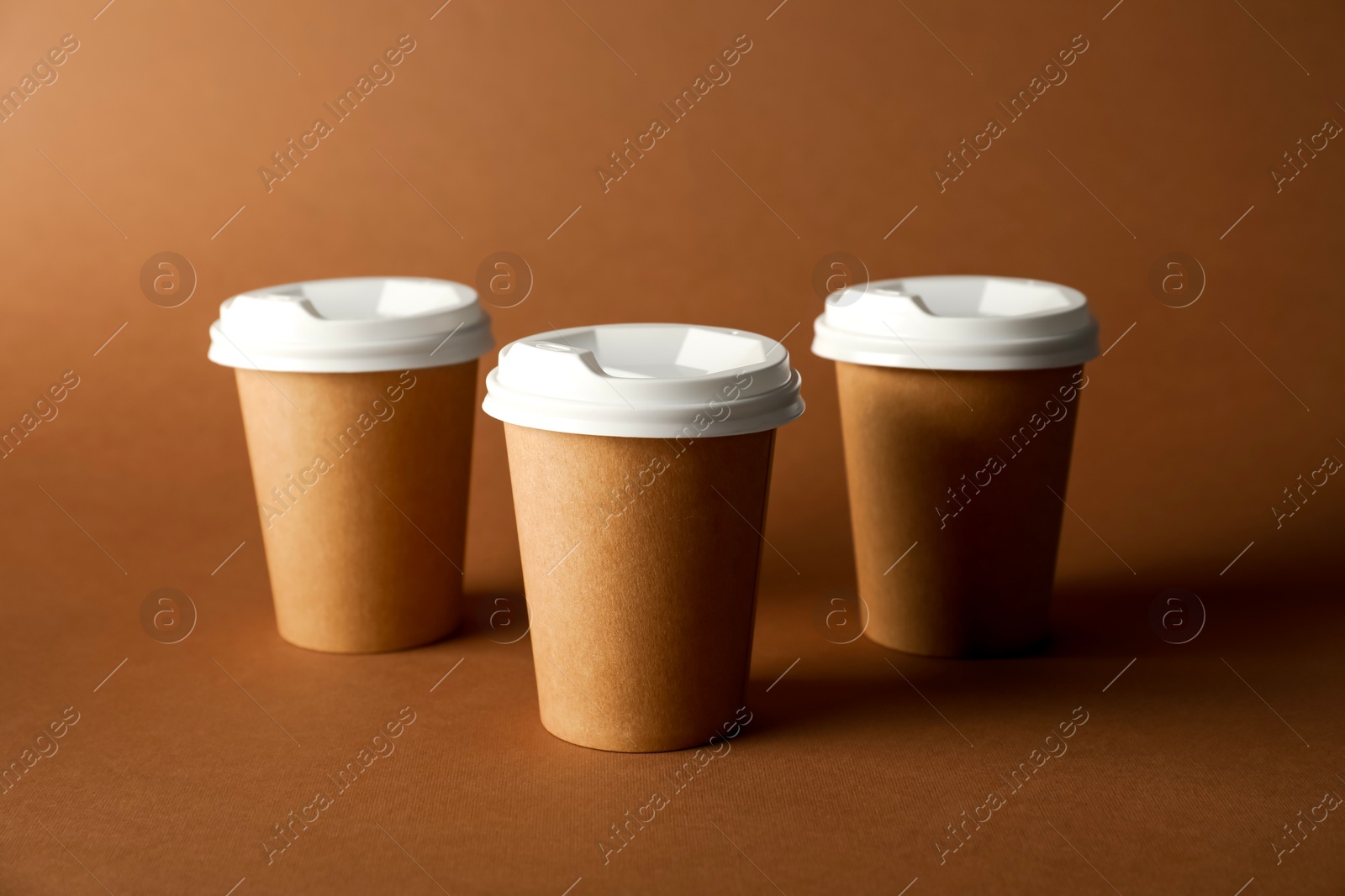 Paper cups with lids on brown background. Mockup for design Photo of Paper cups with lids on brown background. Mockup for design