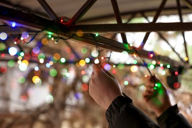 Photo of Man decorating house with Christmas lights outdoors, closeup. Space for text