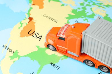 Photo of Toy truck on world map, closeup. Logistics concept