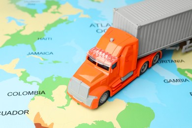 Photo of Toy truck on world map, closeup. Logistics concept