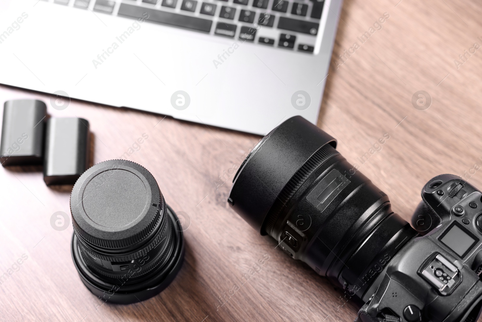 Photo of Professional photo camera, lens and laptop on wooden desk, above view