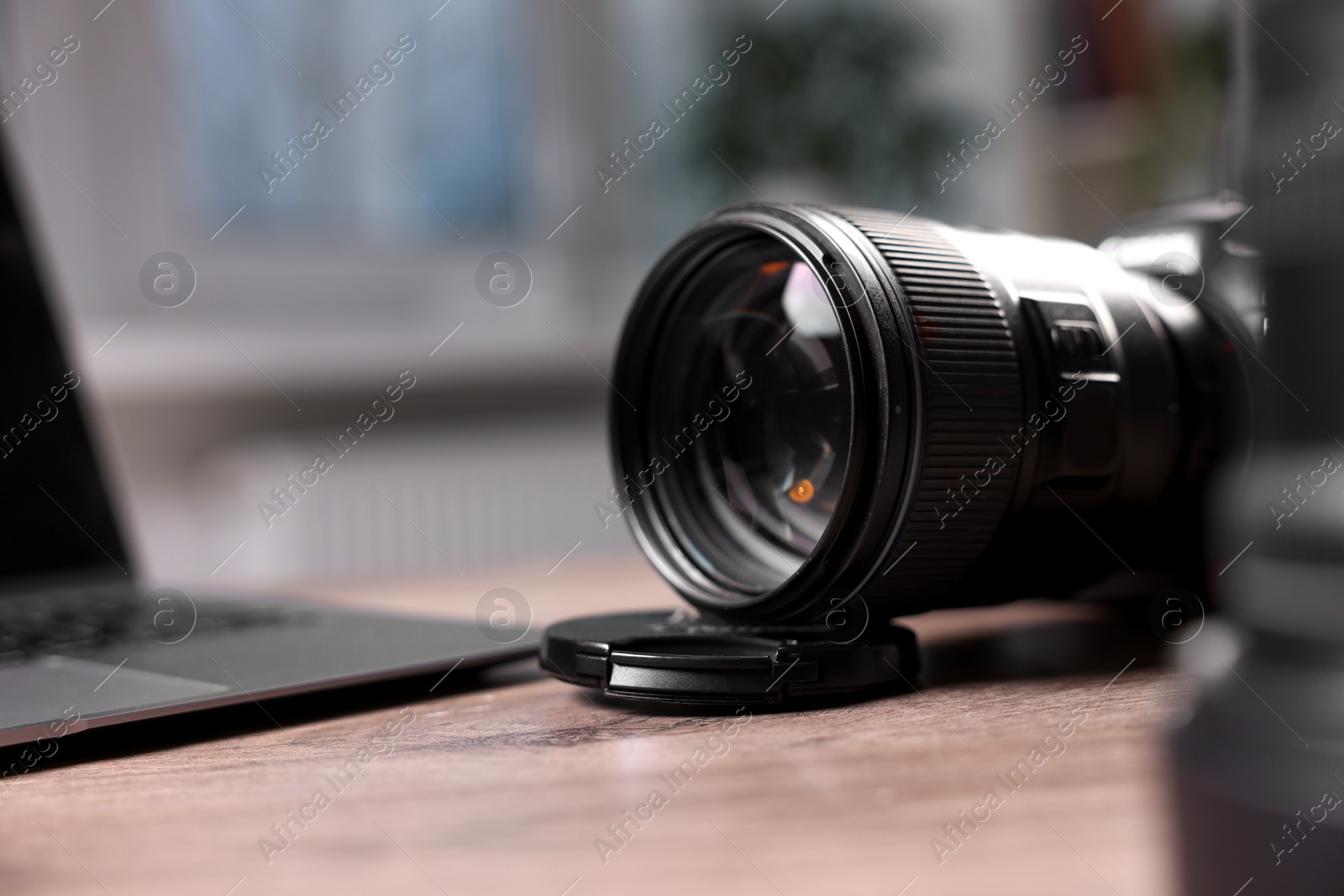 Photo of Professional photo camera and laptop on wooden desk, selective focus. Space for text