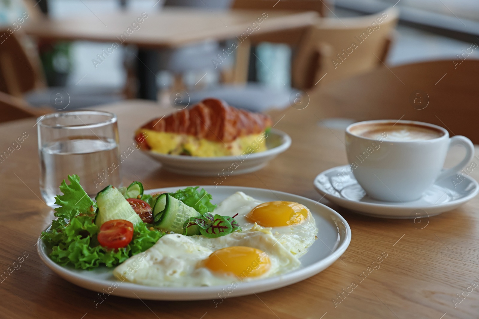 Photo of Delicious breakfast served on wooden table in cafe, closeup