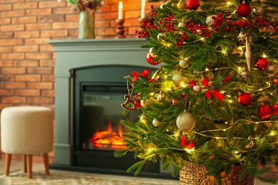 Photo of Beautiful decorated Christmas tree near fireplace at home, closeup. Space for text