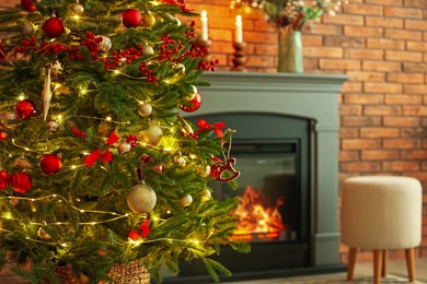 Photo of Beautiful decorated Christmas tree near fireplace at home, closeup. Space for text