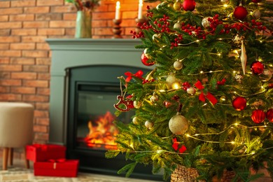 Photo of Beautiful decorated Christmas tree near fireplace at home, closeup. Space for text