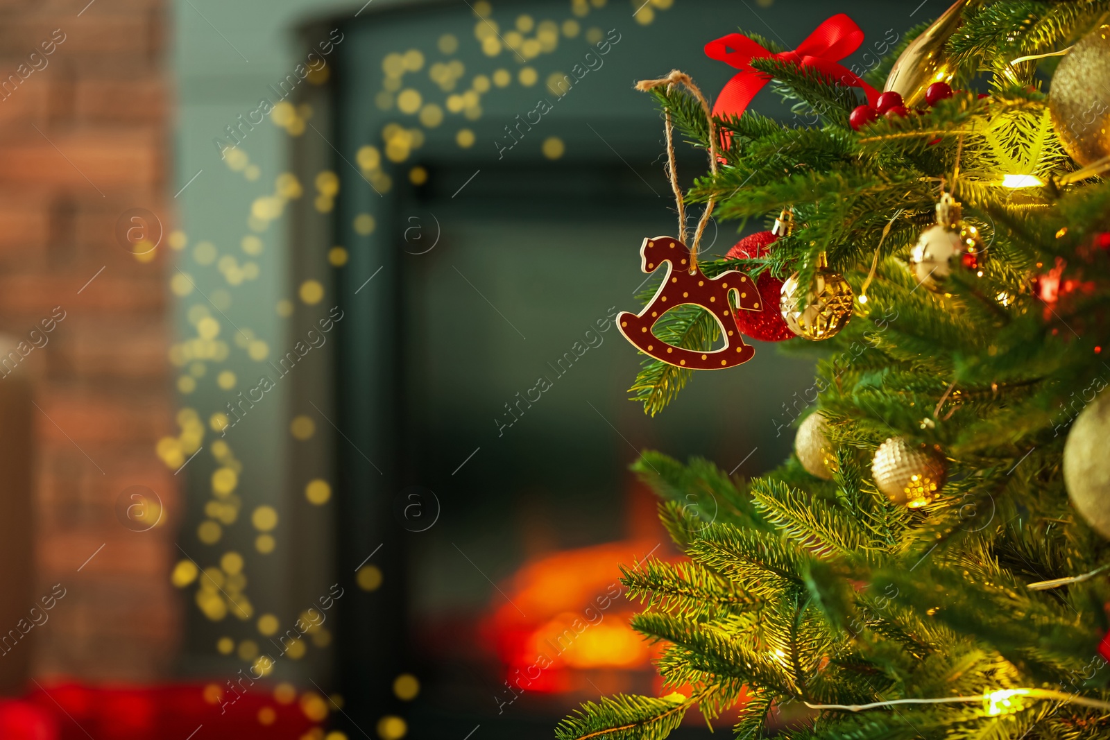 Photo of Beautiful Christmas tree decorated with horse toy, other ornaments and festive lights near fireplace at home, closeup. Space for text