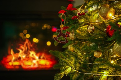 Photo of Beautiful Christmas tree decorated with horse toy, other ornaments and festive lights near fireplace at home, closeup. Bokeh effect