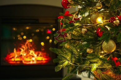 Photo of Beautiful Christmas tree decorated with horse toy, other ornaments and festive lights near fireplace at home, closeup. Bokeh effect