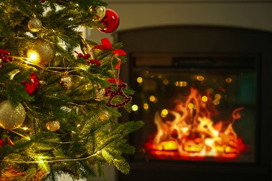 Photo of Beautiful Christmas tree decorated with horse toy, other ornaments and festive lights near fireplace at home, closeup. Bokeh effect