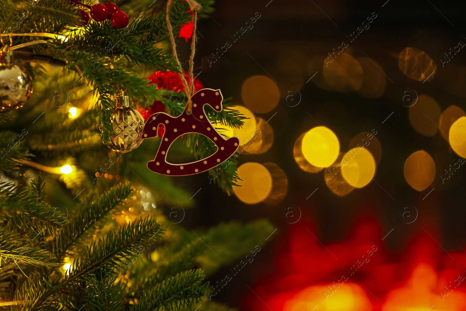 Photo of Beautiful Christmas tree decorated with horse toy, other ornaments and festive lights indoors, closeup. Bokeh effect