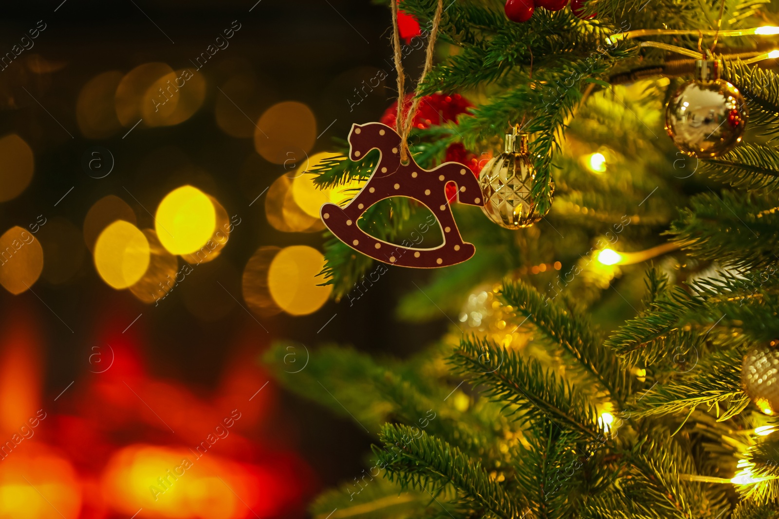 Photo of Beautiful Christmas tree decorated with horse toy, other ornaments and festive lights indoors, closeup. Bokeh effect