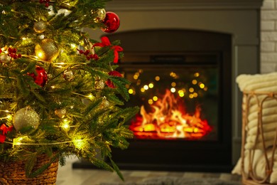 Photo of Beautiful decorated Christmas tree near fireplace at home, closeup. Bokeh effect