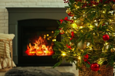 Photo of Beautiful decorated Christmas tree near fireplace at home, closeup. Bokeh effect