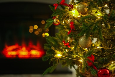 Photo of Beautiful decorated Christmas tree near fireplace at home, closeup. Bokeh effect