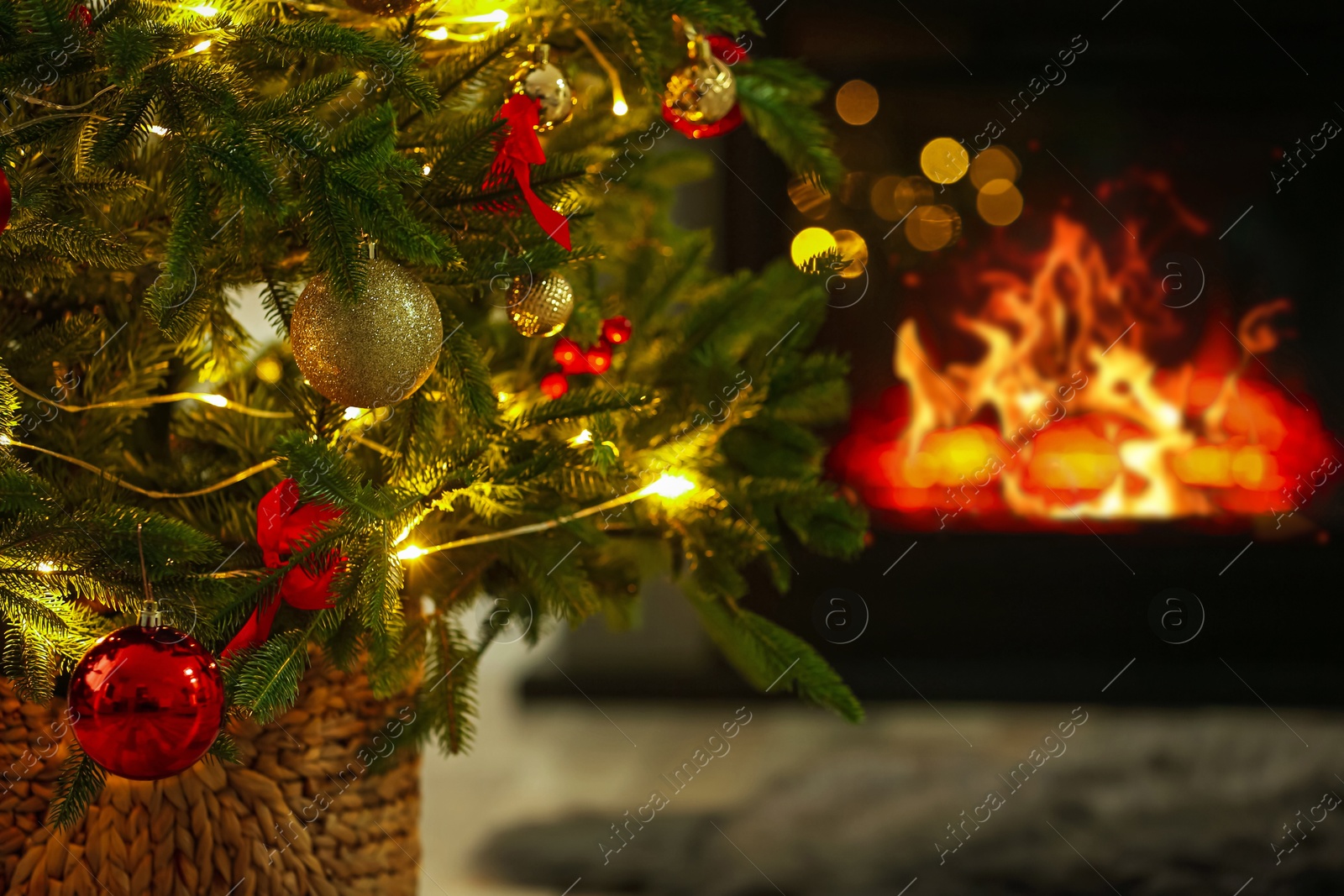 Photo of Beautiful decorated Christmas tree near fireplace at home, closeup. Bokeh effect