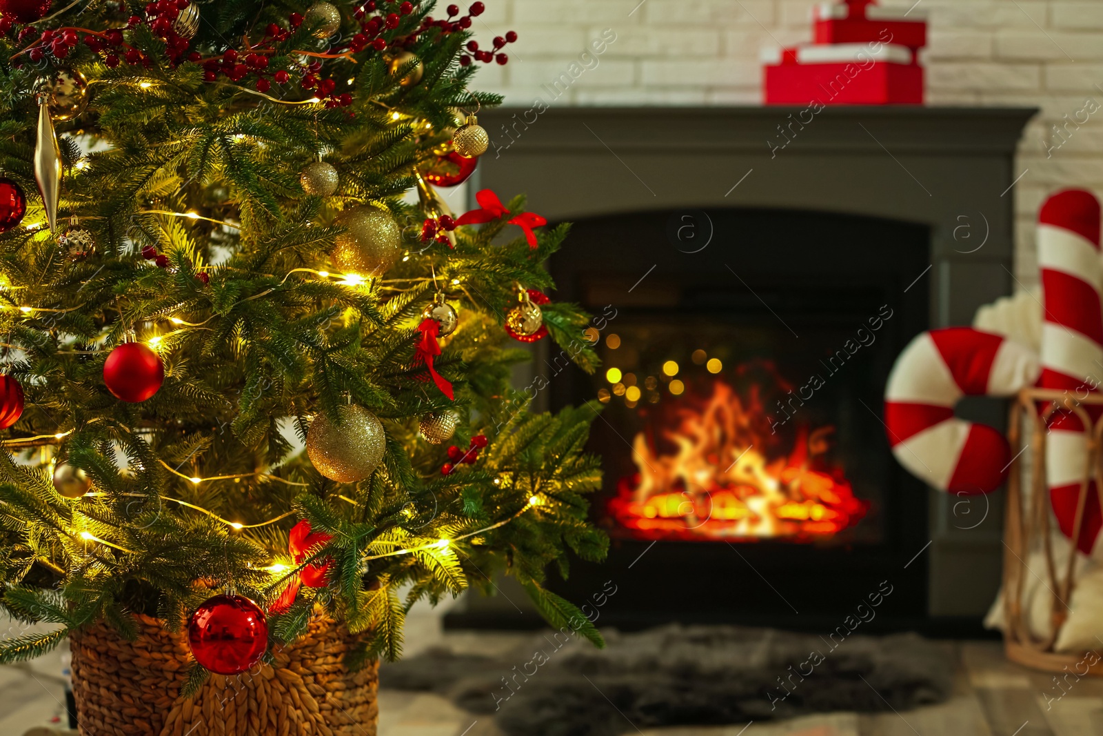 Photo of Beautiful decorated Christmas tree near fireplace at home, closeup. Bokeh effect