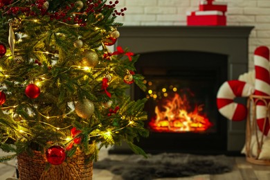 Photo of Beautiful decorated Christmas tree near fireplace at home, closeup. Bokeh effect