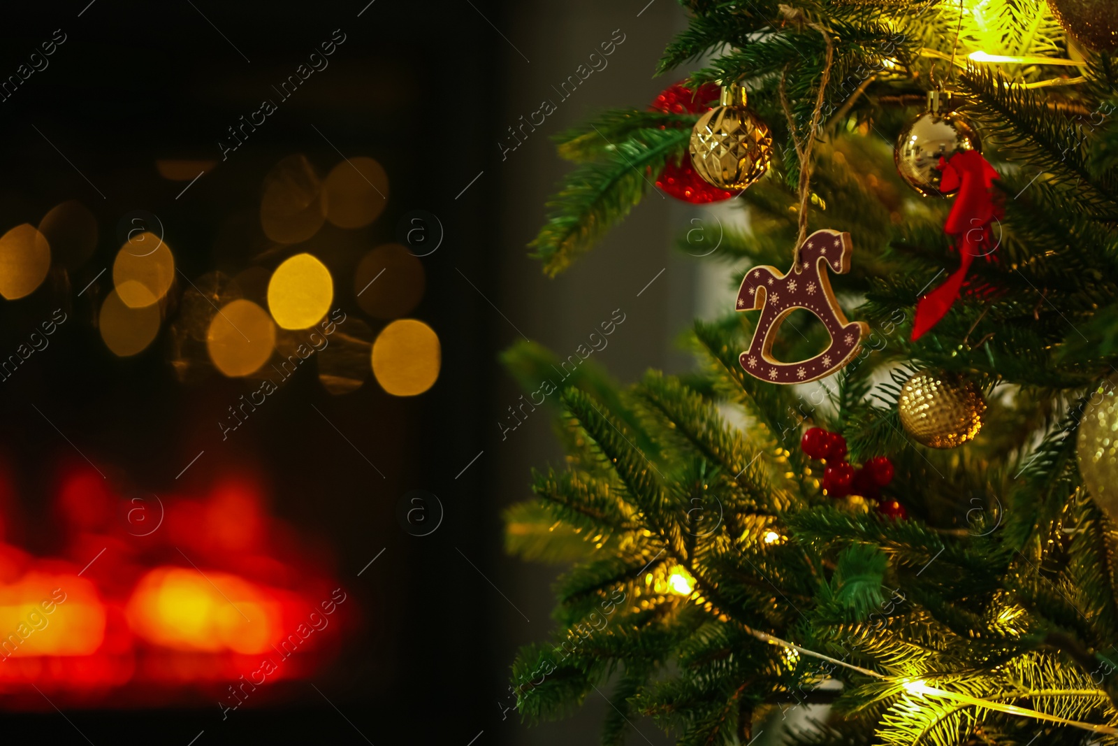 Photo of Beautiful Christmas tree decorated with horse toy, other ornaments and festive lights indoors, closeup. Bokeh effect