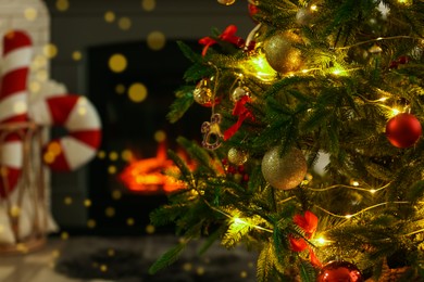 Photo of Beautiful decorated Christmas tree near fireplace at home, closeup. Space for text