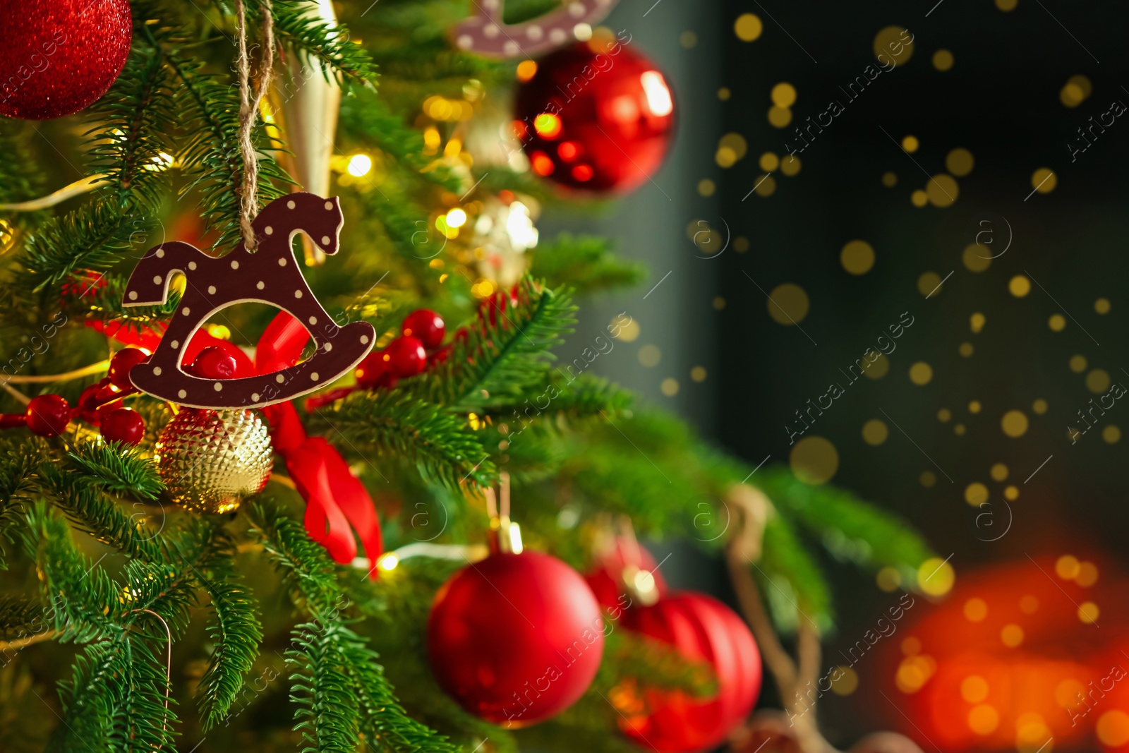 Photo of Beautiful Christmas tree decorated with horse toy, other ornaments and festive lights indoors, closeup. Space for text