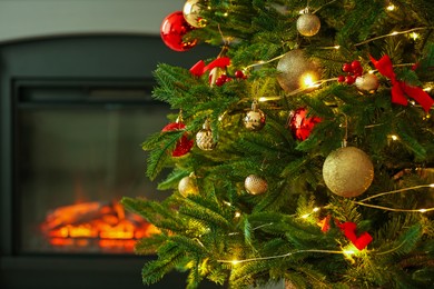 Photo of Beautiful decorated Christmas tree near fireplace at home, closeup. Space for text