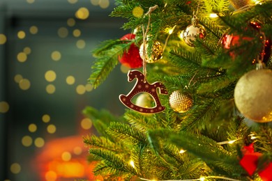 Photo of Beautiful Christmas tree decorated with horse toy, other ornaments and festive lights indoors, closeup. Space for text