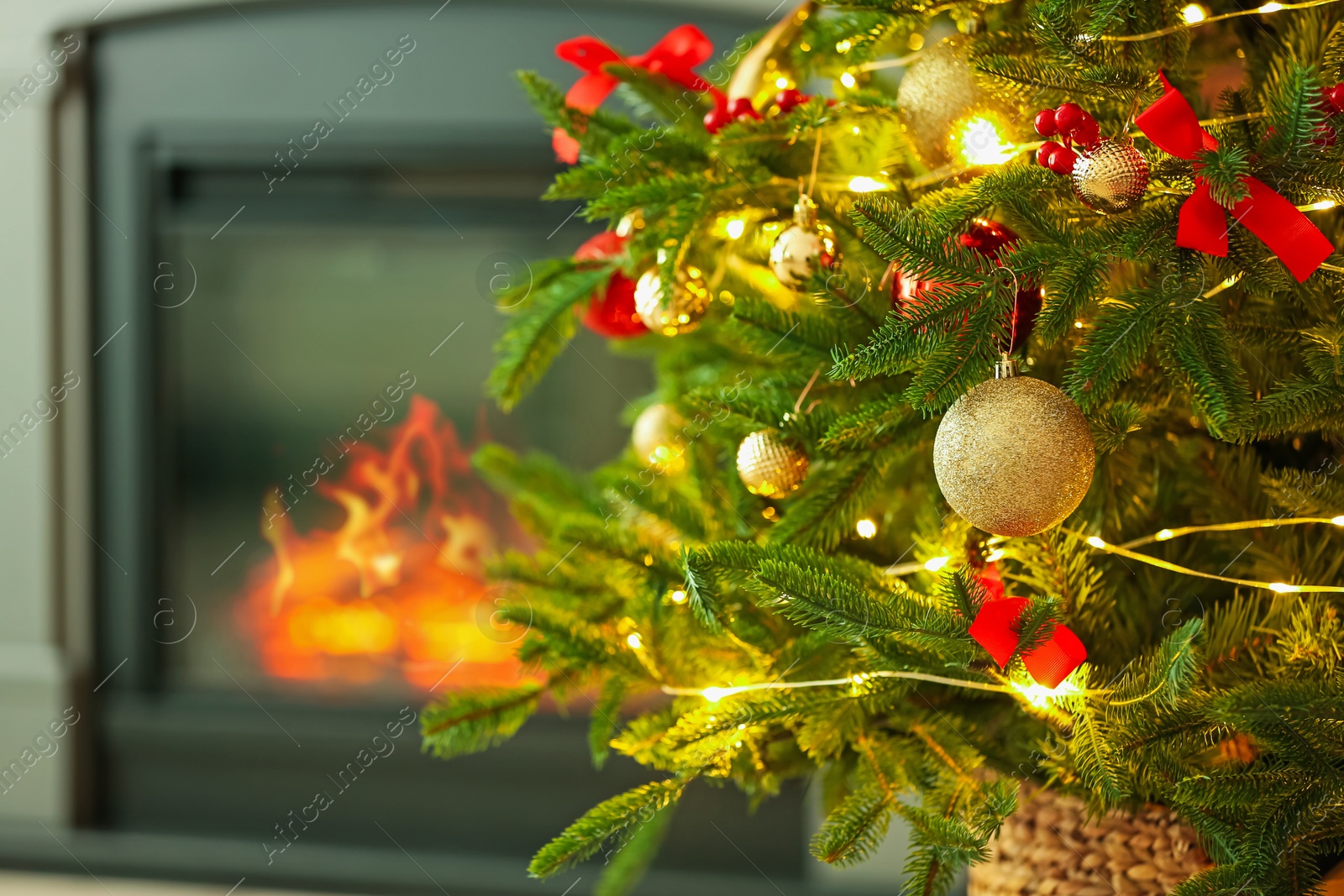 Photo of Beautiful decorated Christmas tree near fireplace at home, closeup. Space for text