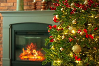 Photo of Beautiful decorated Christmas tree near fireplace at home, closeup. Space for text