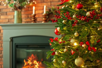 Photo of Beautiful decorated Christmas tree near fireplace at home, closeup. Space for text