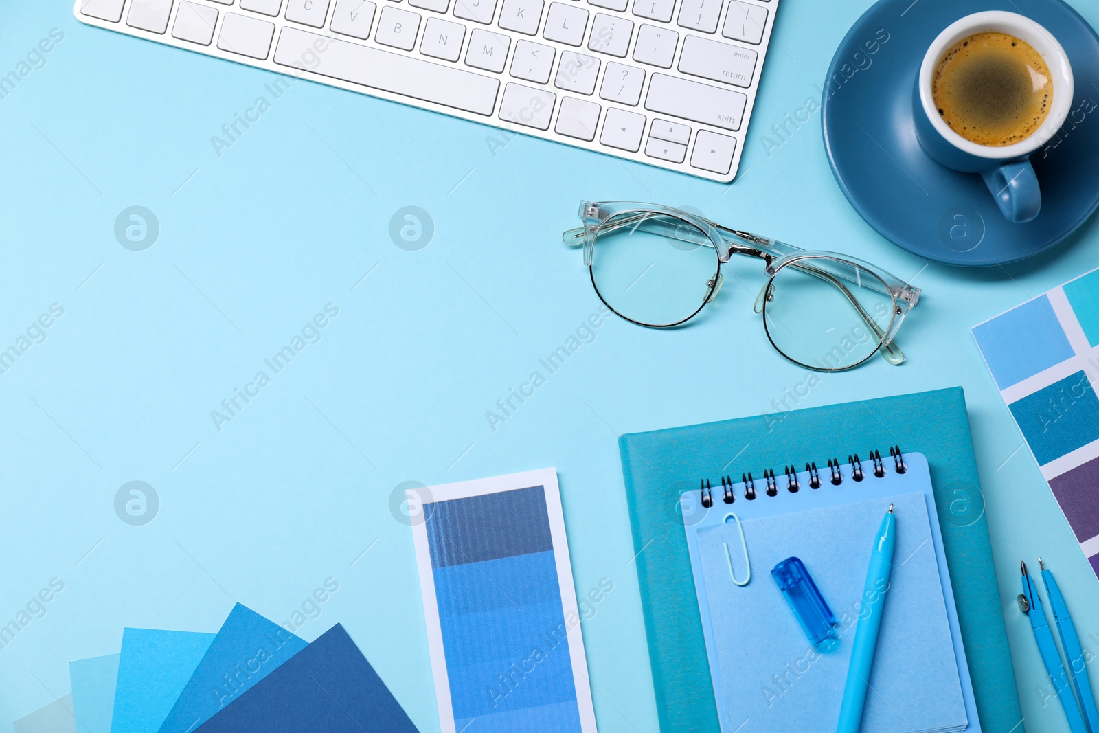 Photo of Designer's workplace. Flat lay composition with stationery and keyboard on light blue background, space for text