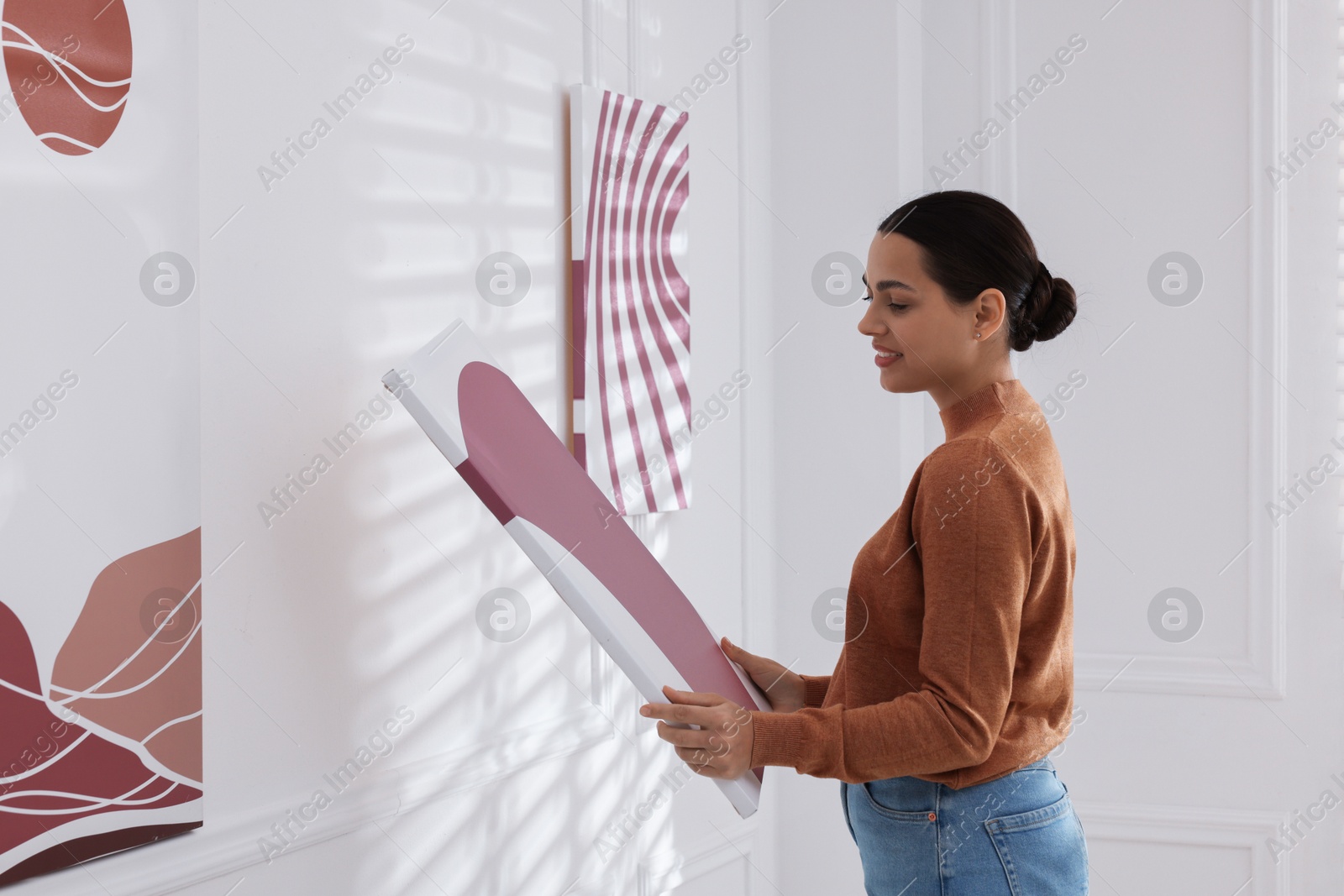 Photo of Woman hanging painting on wall in art gallery