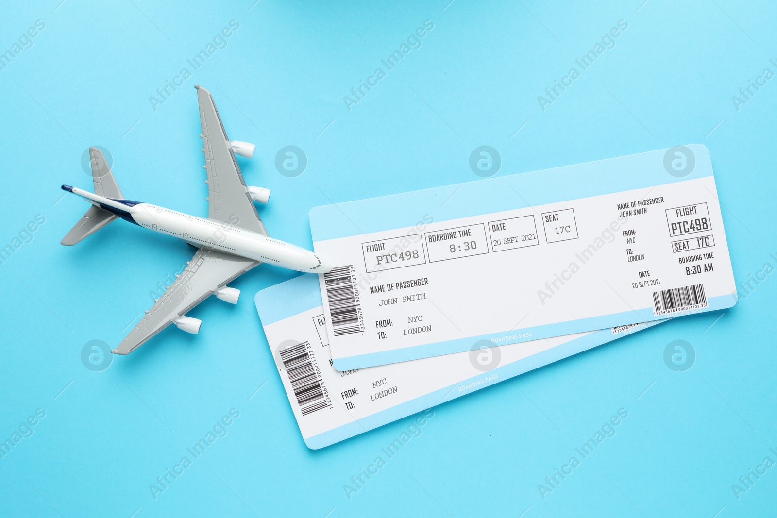 Photo of Travel agency. Flight tickets and plane model on light blue background, flat lay