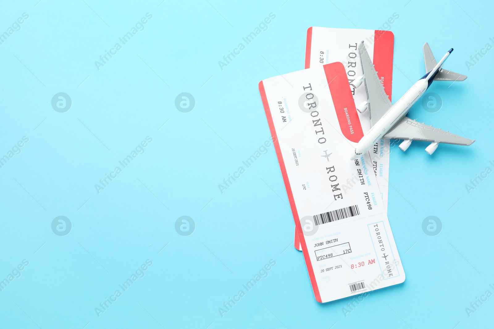 Photo of Travel agency. Flight tickets and plane model on light blue background, flat lay. Space for text