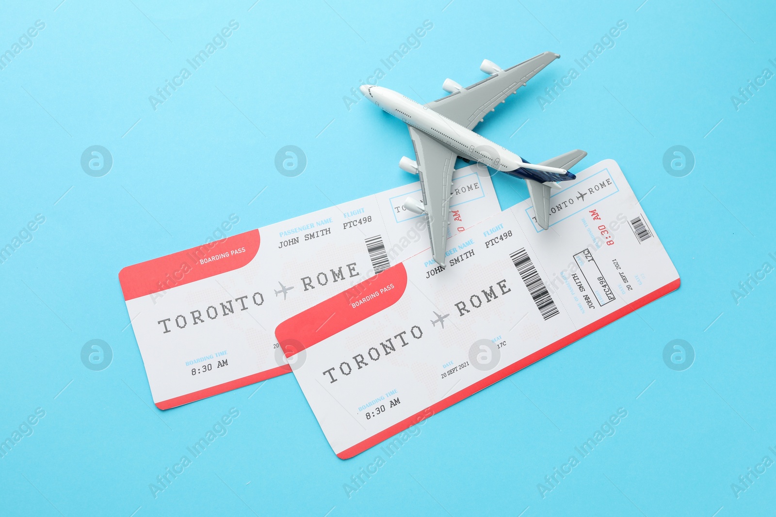 Photo of Travel agency. Flight tickets and plane model on light blue background, flat lay