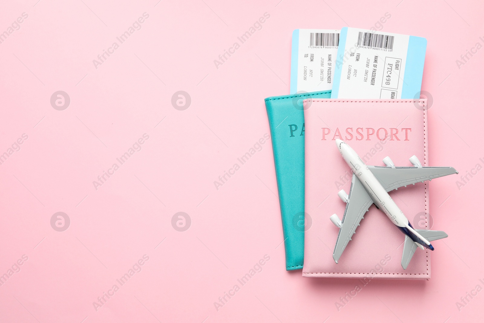 Photo of Travel agency. Flight tickets, passports and plane model on pink background, top view. Space for text