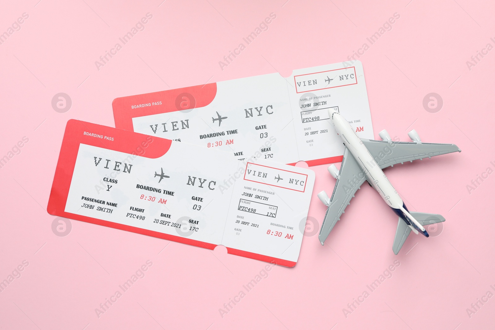 Photo of Travel agency. Flight tickets and plane model on pink background, flat lay