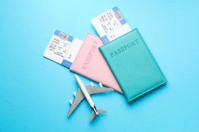 Photo of Travel agency. Flight tickets, passports and plane model on light blue background, top view