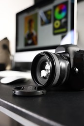 Photo of Professional camera and computer on black desk indoors, selective focus