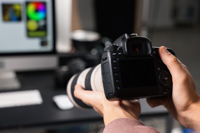 Photo of Photographer with professional camera at desk indoors, closeup