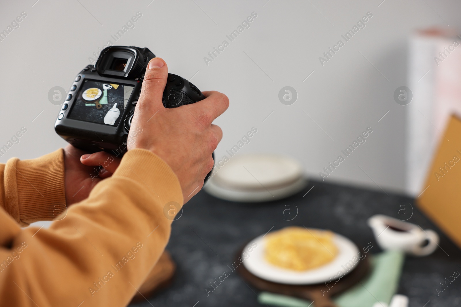 Photo of Man taking photo of crepes with professional camera in studio, closeup. Selective focus