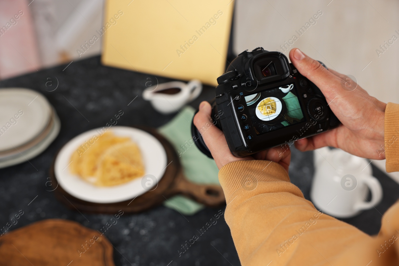 Photo of Man taking photo of crepes with professional camera in studio, closeup. Selective focus