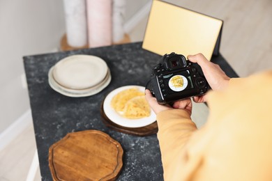 Photo of Man taking photo of crepes with professional camera in studio, closeup. Selective focus