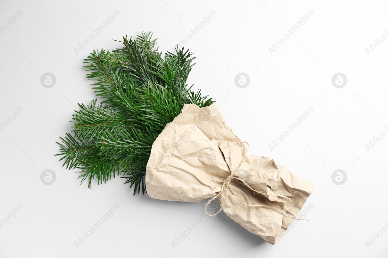 Photo of Christmas bouquet. Green fir branches wrapped in kraft paper on light background, top view