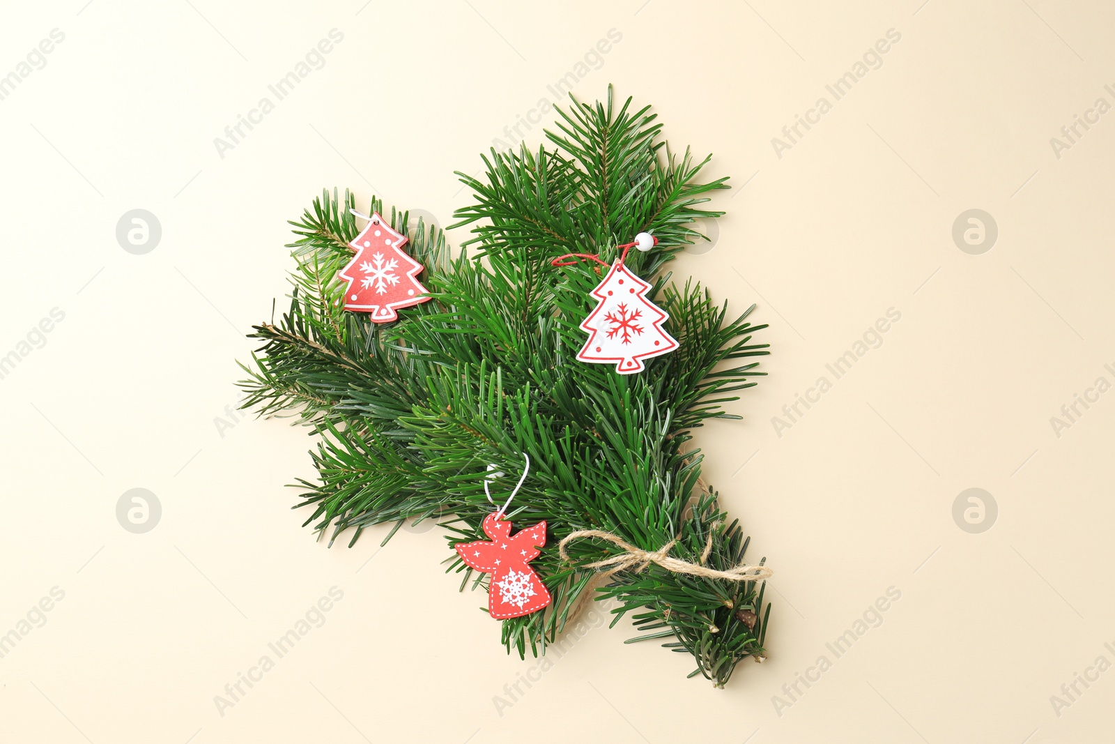 Photo of Festive bouquet of green fir branches with Christmas decor on beige background, top view