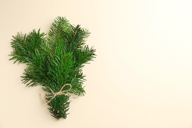 Photo of Christmas bouquet. Green fir branches tied on beige background, top view. Space for text