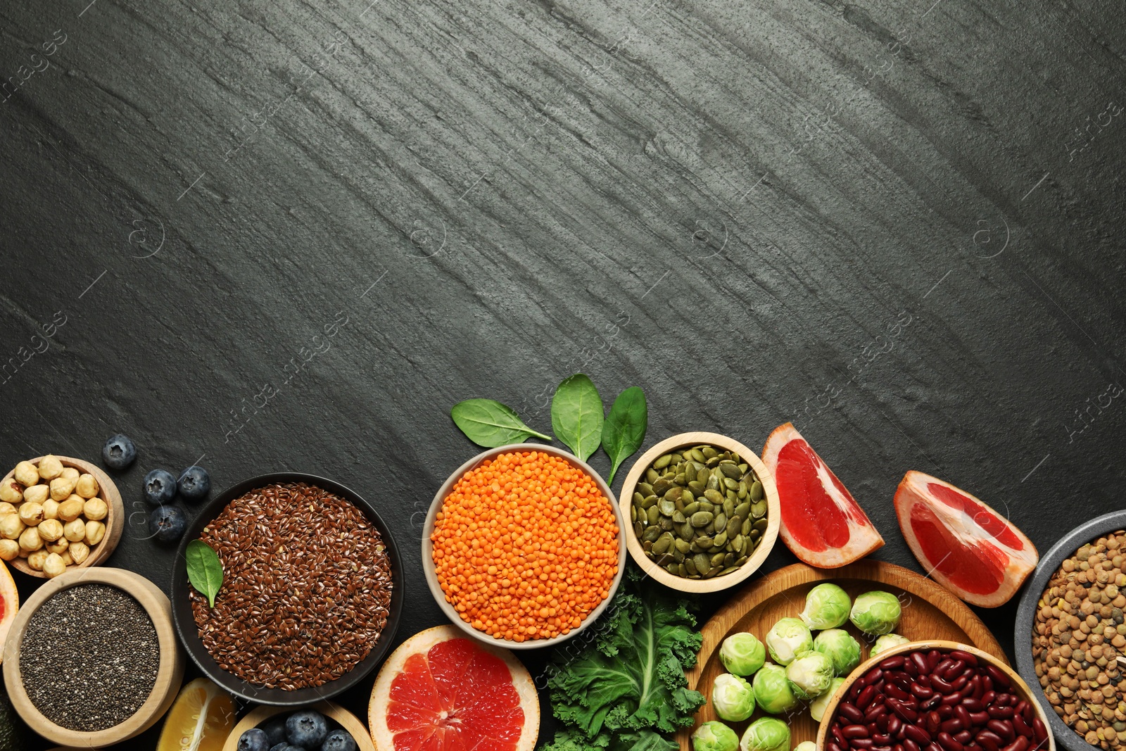 Photo of Different superfood products on black table, flat lay. Space for text